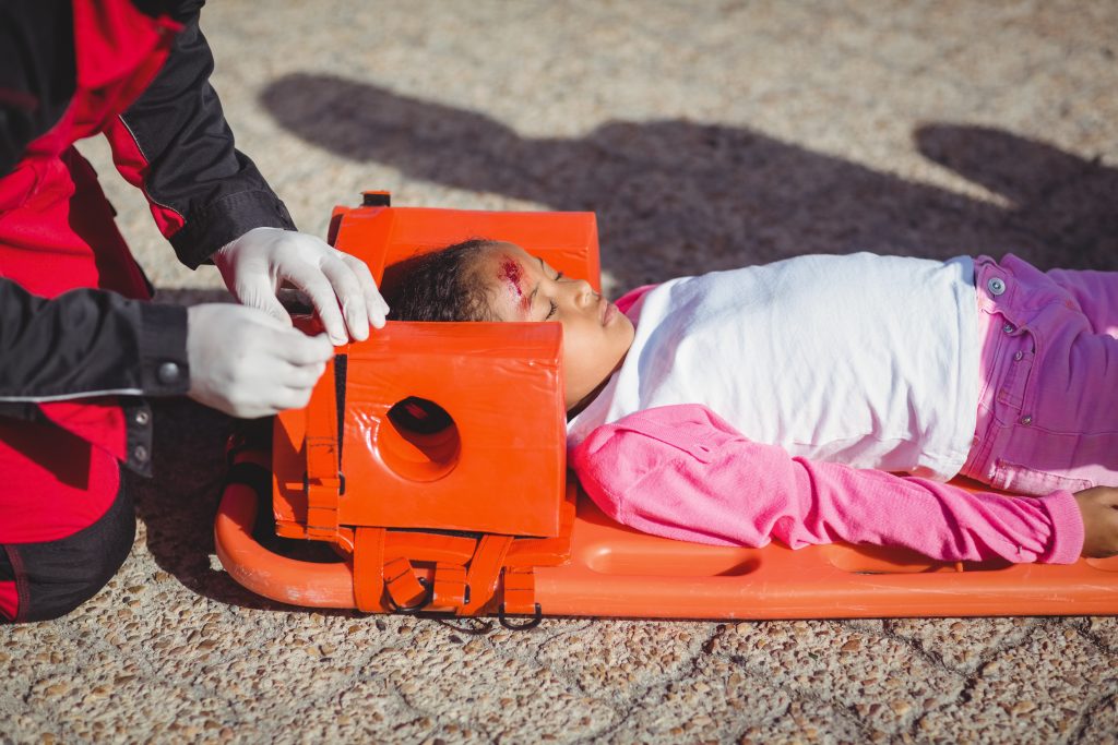 A young girl with a head injury being treated by a paramedic on a stretcher. This image highlights the critical need for emergency legal services during health crises, emphasizing the importance of having reliable legal support to protect your rights and well-being in urgent situations.