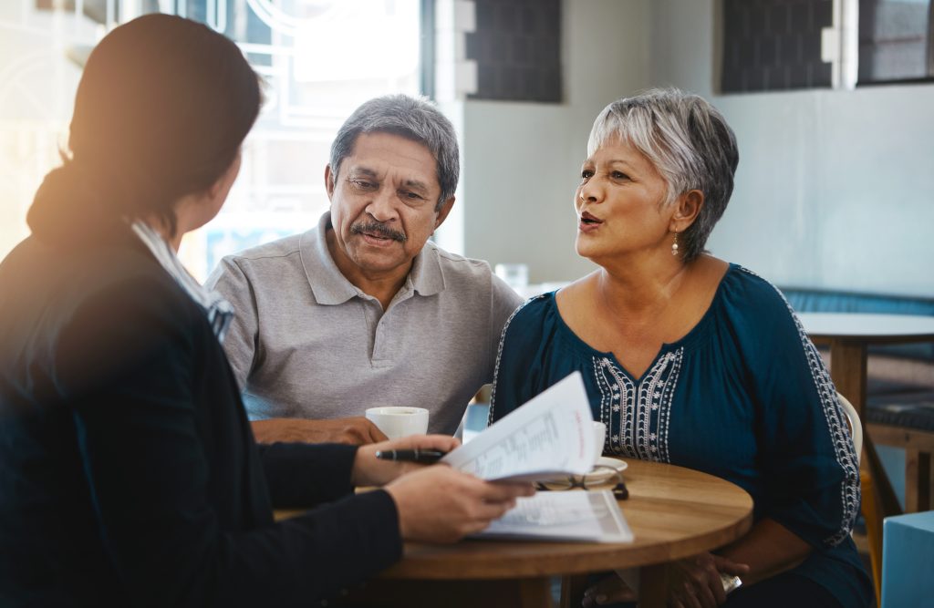 A senior couple consults with a lawyer, discussing documents related to estate planning and probate in Illinois. This image reflects the importance of integrating estate planning with family law to ensure that a family's wishes are respected and their assets are protected, minimizing the complexities of probate.