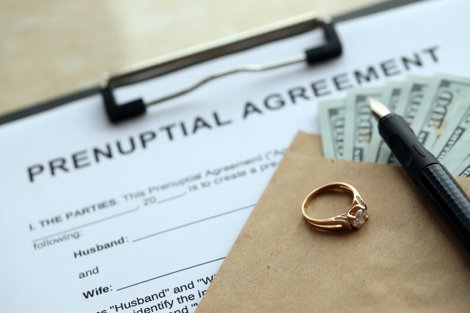 Prenuptial agreement and wedding ring on table. Premarital paperwork process in USA close up